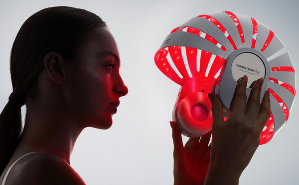 Woman holding the CurrentBody LED red light helmet for scalp health